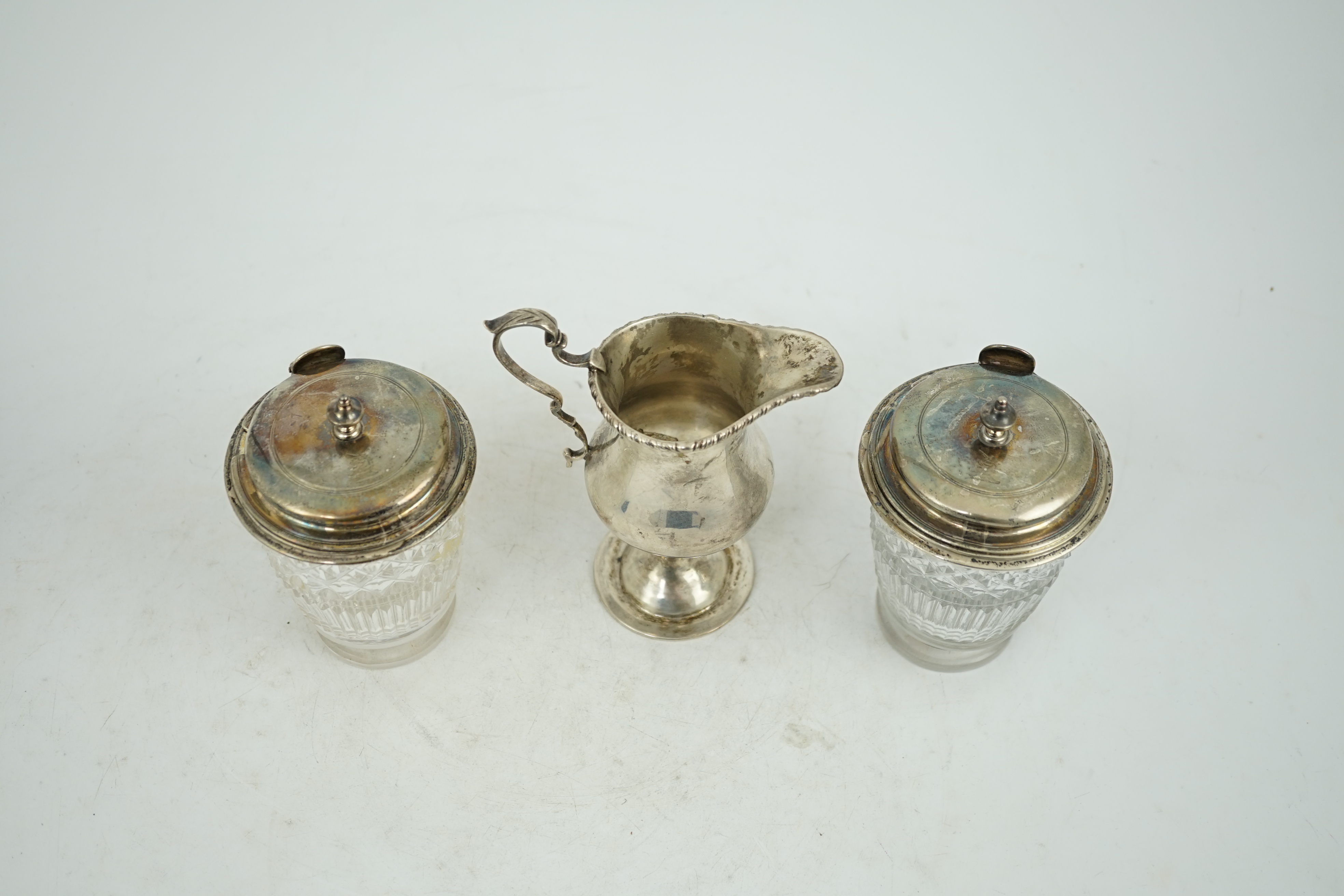 Two George III silver mounted glass cruet bottles, London, 1808, height 12.6cm and a late Victorian silver inverted pear shaped cream jug.